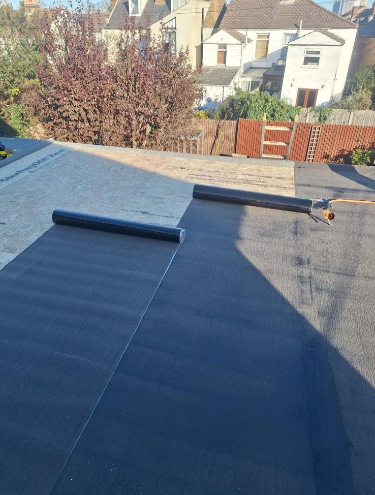 new felt being measured out for flat roof replacement